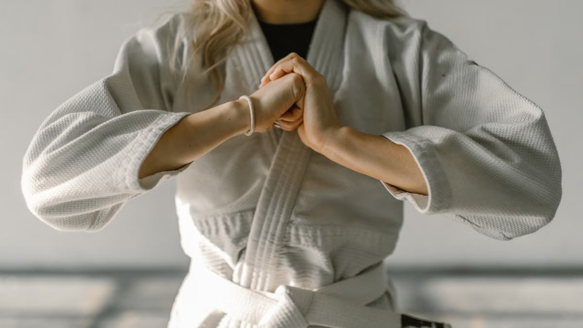 Close-up of a karate practitioner in white gi performing a hand gesture indoors.